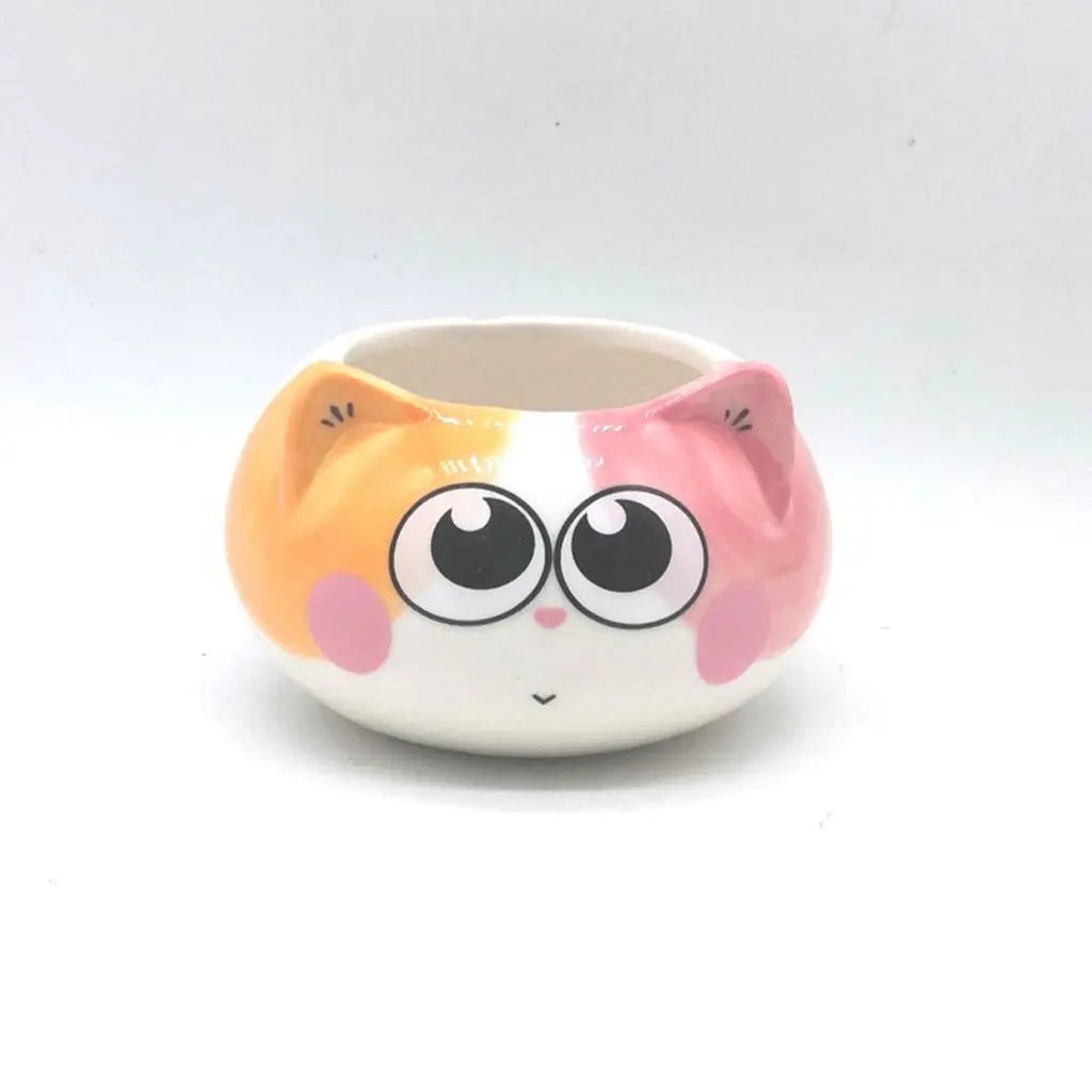 Ceramic cat face planter with large eyes, pink ears, and orange-and-white rim