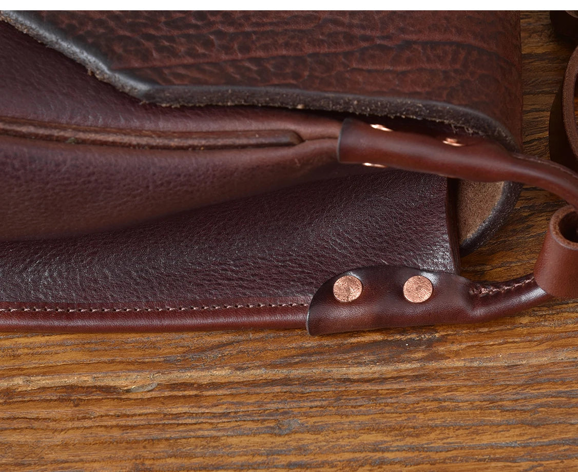 Vintage brown genuine cowhide messenger bag with visible texture, reinforced copper rivets, and detailed stitching.