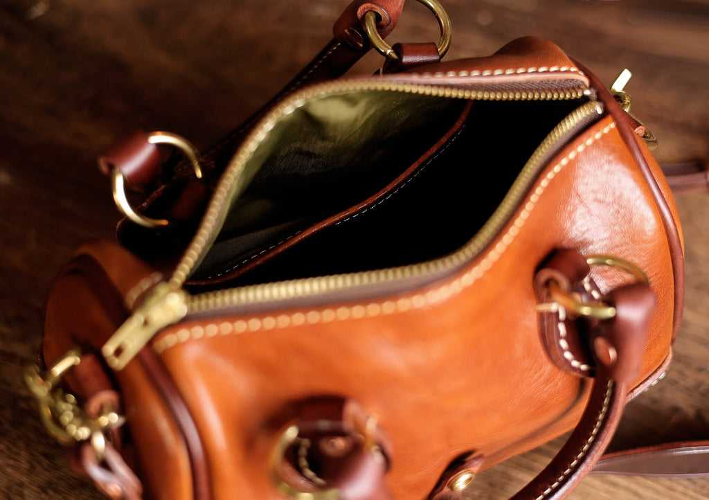 Vintage PNDME small brown genuine cowhide leather designer handbag with brass hardware and zip-top opening.
