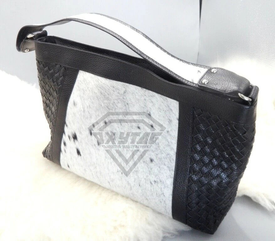 Black woven leather designer handbag with white cowhide fur patchwork center panel and single shoulder strap.