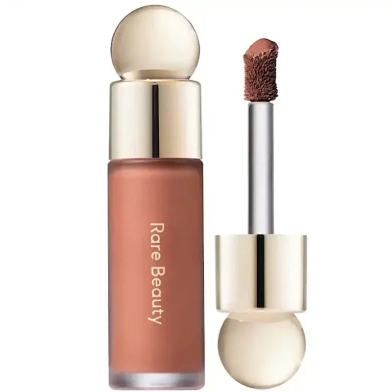 Rare Beauty matte liquid lipstick in a rich nude shade with applicator brush, featuring a smooth, moisture-rich texture.