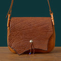 Vintage brown genuine cowhide messenger bag with textured flap, silver stud closure, and beaded leather cord detail.