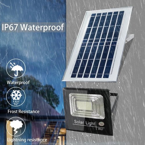 Black LED solar floodlight and solar panel mounted on a wall during heavy rain.