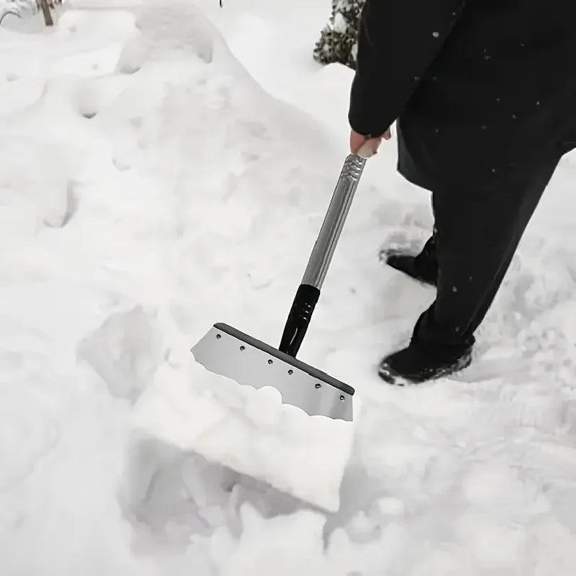 Snow and ice cleaning shovel with silver blade and wood handle, scraping through packed snow