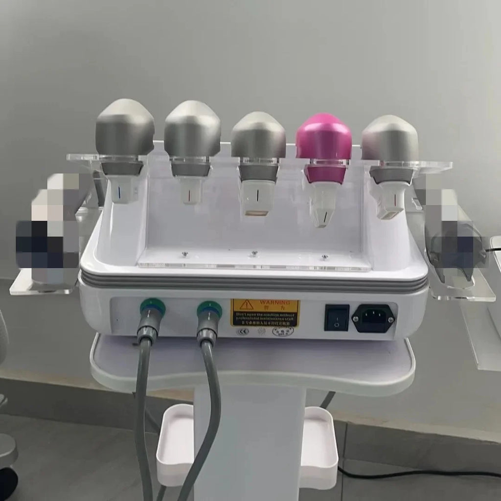 Professional beauty machine with five silver and pink treatment probes held in a white acrylic stand on a pedestal.