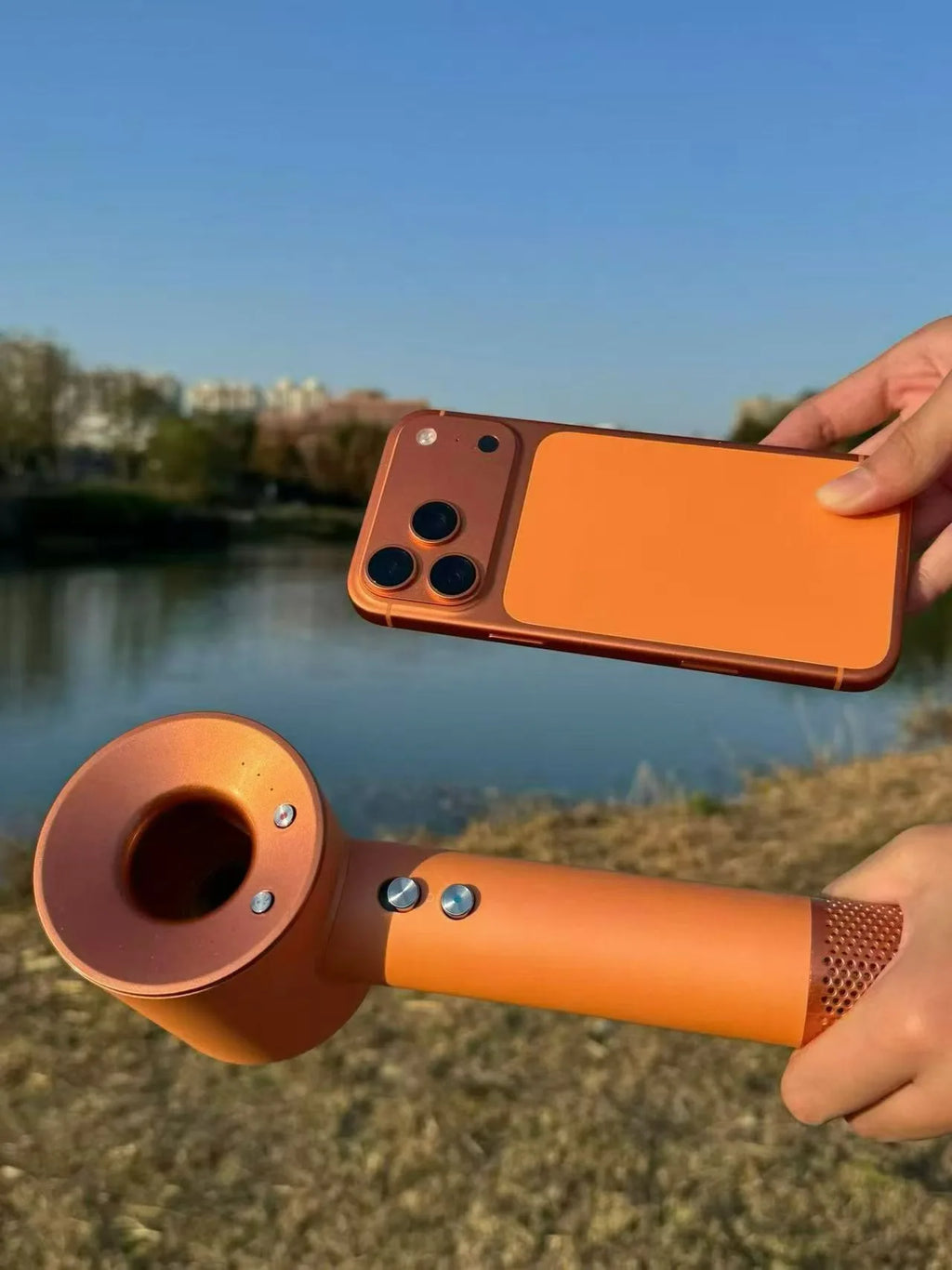 Orange high-speed negative ion bladeless hair dryer with magnetic attachments and ergonomic handle outdoors.