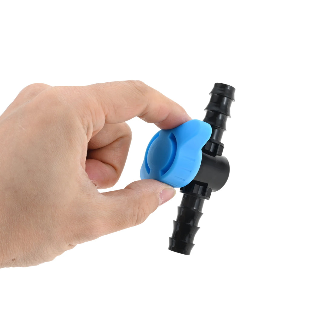 Hand holding 1/2 in drip irrigation shut-off valve with blue latch and black barbs