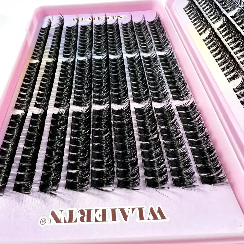 Rows of black individual lash clusters in a pink plastic tray for professional eyelash extensions.