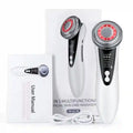 White, ergonomic EMS facial massager with a circular metal head featuring red LED lights, plus packaging and USB cord.