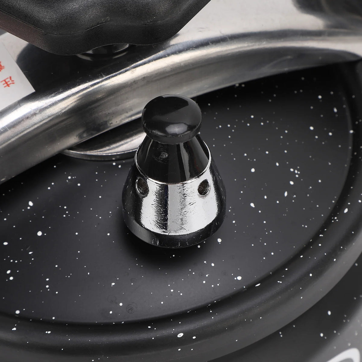 Black pressure canner valve with black cap on metal stem over speckled lid