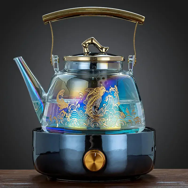 Iridescent glass tea kettle with gold koi fish design, brass handle, and matching electric heating base.