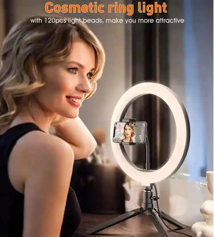 Black circular LED ring light on a tripod stand with an integrated smartphone mount for filming or makeup application.