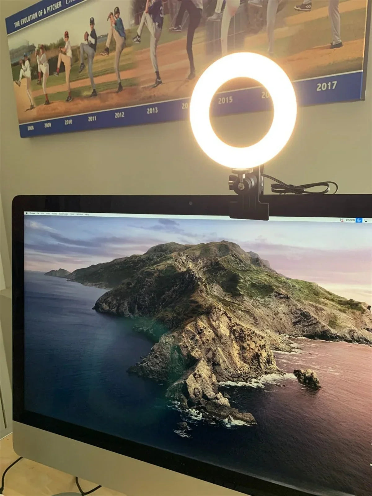 Small, circular LED ring light with a black clip mounted on top of a computer monitor for video calls and lighting.