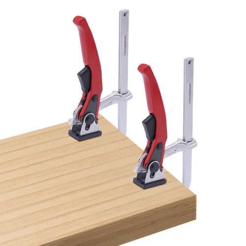 Pair of track saw guide rail clamps with red handles on a light wood board, alloy steel