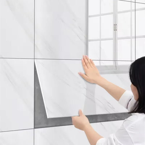 White marble-look tile sticker sheets being applied to a wall by hands