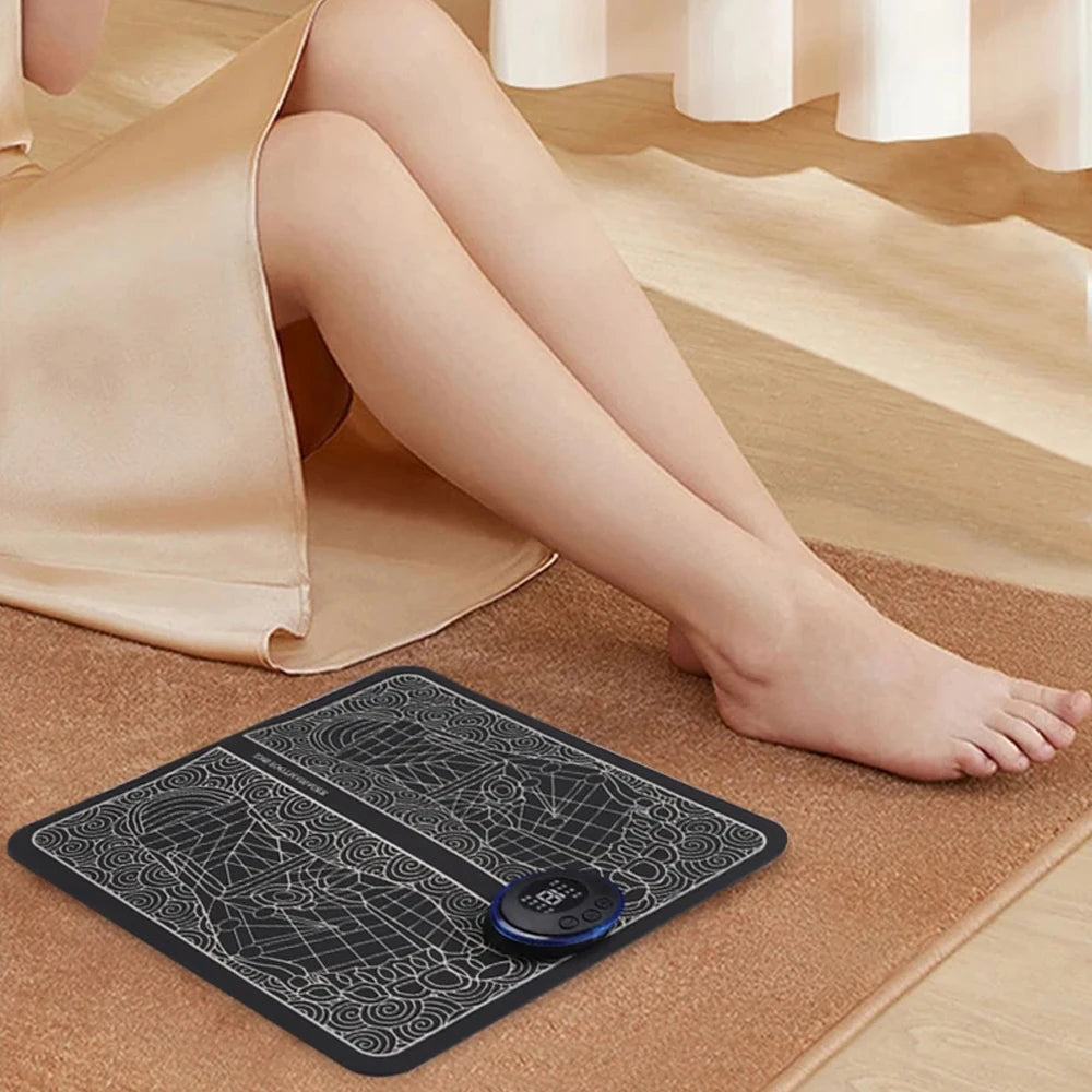 Black foldable EMS electric foot massager mat with digital control unit for home relaxation and sore foot relief.