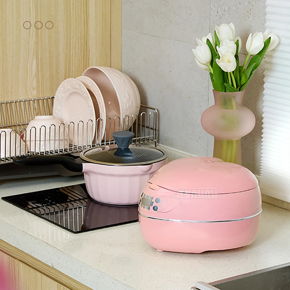 Pink heart-shaped mini rice cooker with closed lid and control panel, on countertop.