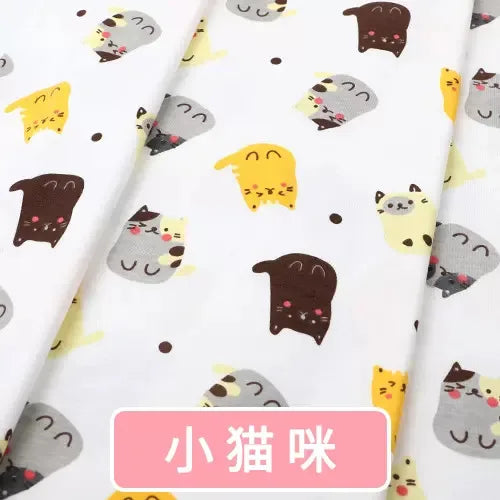 Soft white Tidesmit knit jersey fabric featuring a colorful repeating print of cute cartoon cats, ideal for baby clothes.