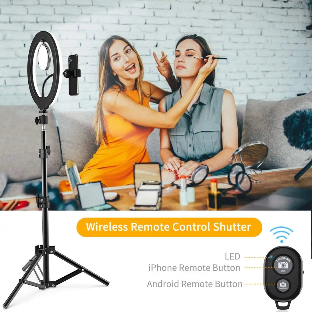 Black metal LED ring light on a tripod stand with phone holder and a wireless remote shutter for mobile photography.