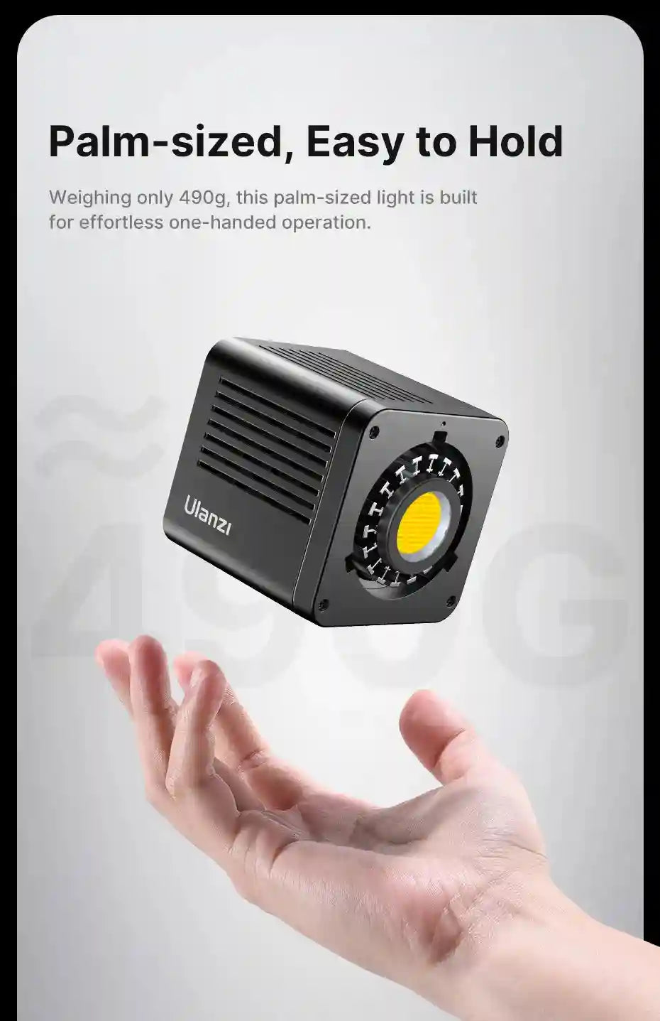 Compact black cube-shaped LED video light hovering above an open palm for portable handheld photography and videography.