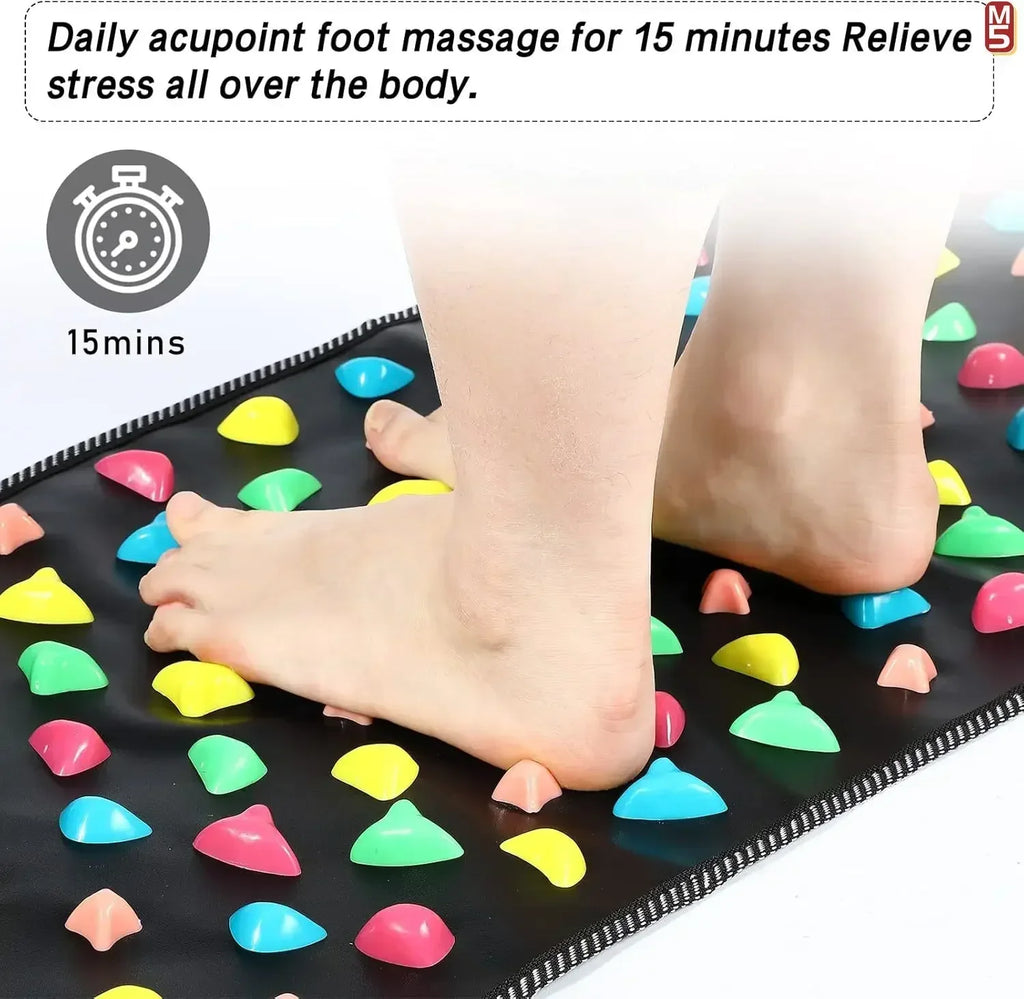 Person standing on a black acupressure foot reflexology massage mat with colorful stimulation stones for pain relief.