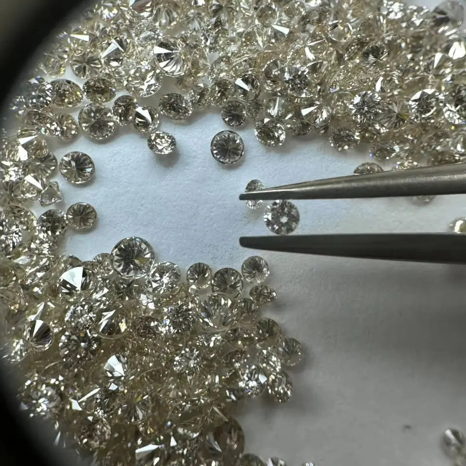 Loose round brilliant diamonds, white, dense scatter with tweezers near center stones