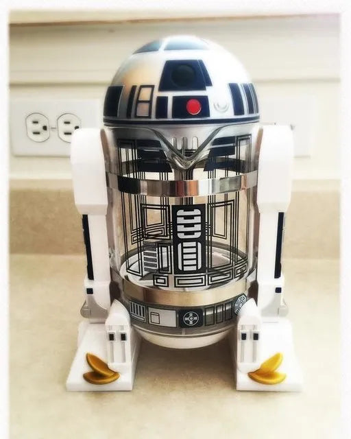 Star Wars R2-D2 glass and plastic French press coffee maker, white and blue robot design on kitchen counter.