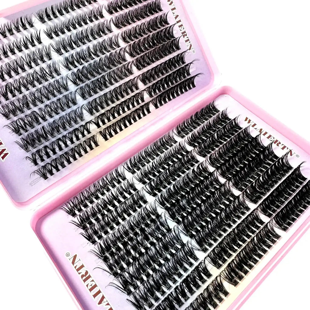 Individual black false eyelash clusters arranged in a two-part pink storage tray for eye makeup application.
