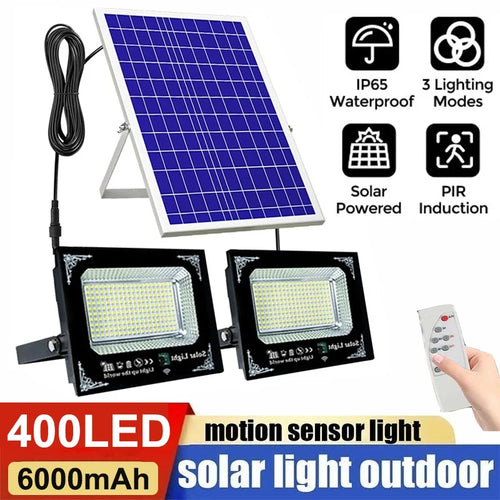 Dual black LED floodlights connected to a blue solar panel, with a remote control and feature icons.