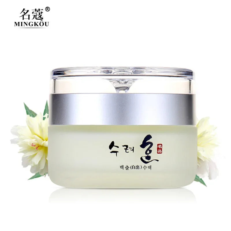 A jar of MINGKOU anti-aging face cream in frosted glass with a silver lid, framed by pale yellow floral accents.