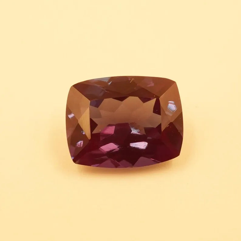 Faceted cushion-cut alexandrite gemstone, dark reddish-brown with reflective highlights