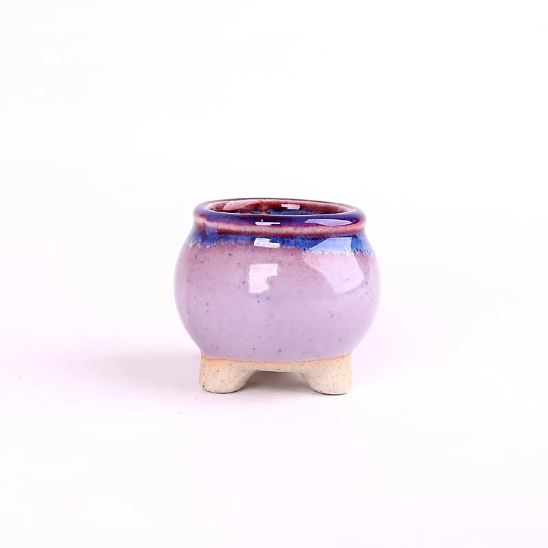 Mini ceramic flowerpot for succulent, lavender-pink glaze with blue rim, glossy finish, three feet.