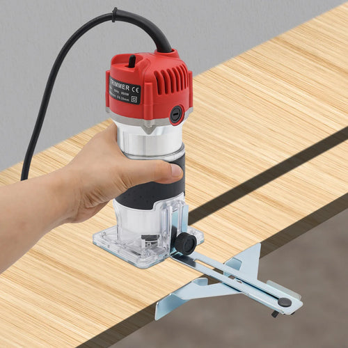 Red and black electric wood router trimmer with clear base, held above wooden board