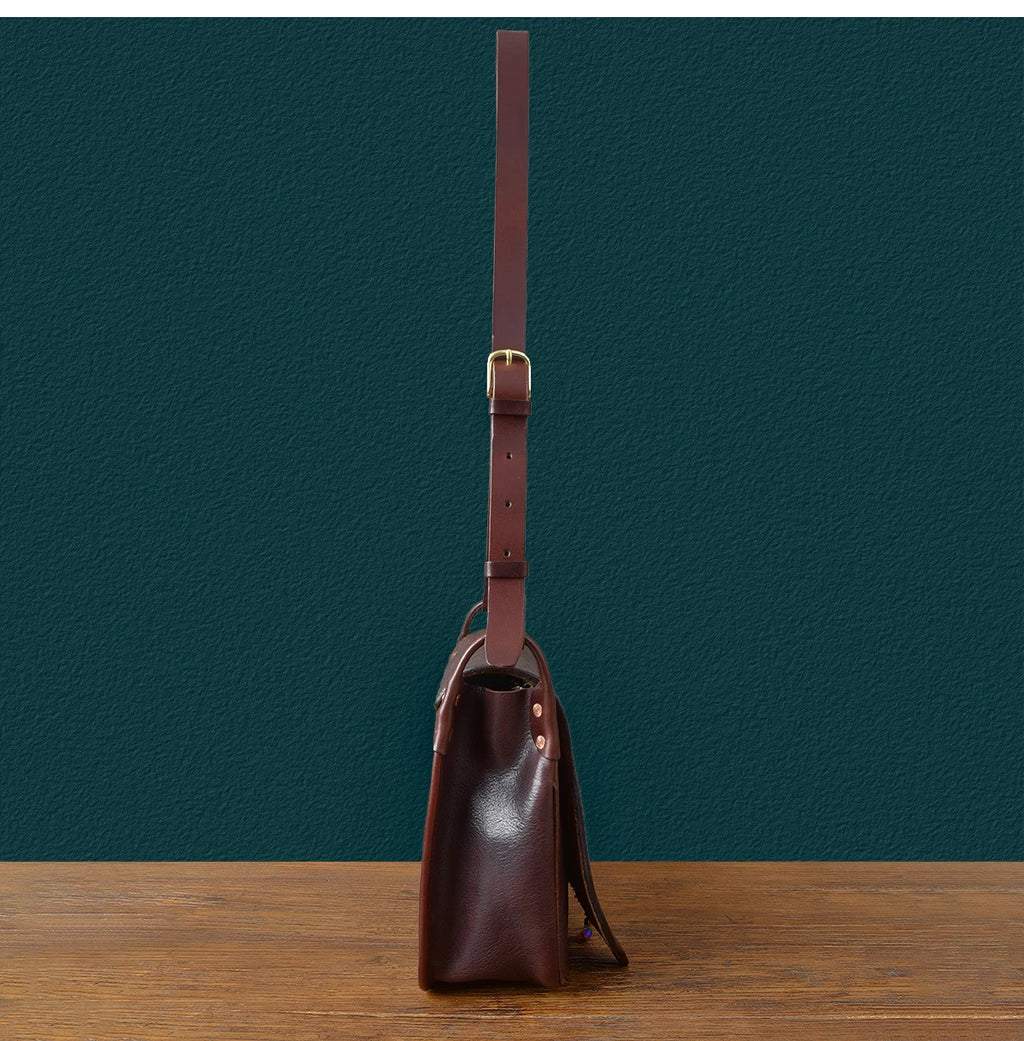 Side view of a vintage handmade dark brown genuine cowhide leather messenger bag with adjustable shoulder strap.