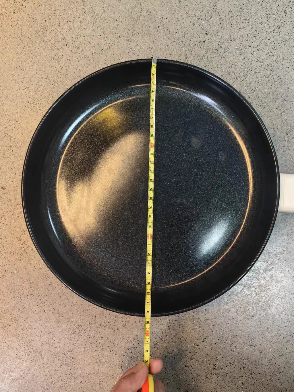 Electric frying pan with black nonstick interior and white body, measured with yellow ruler