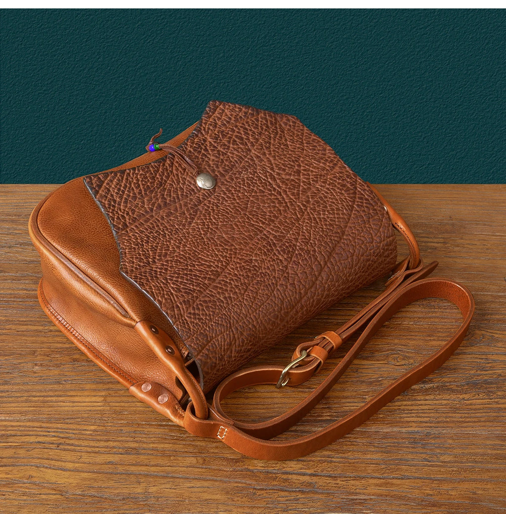 Vintage brown genuine cowhide messenger bag with textured flap, adjustable shoulder strap, and handmade designer style.