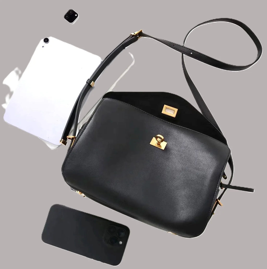Royaa black genuine leather shoulder bag with gold turn-lock closure, adjustable strap, and elegant classic design.
