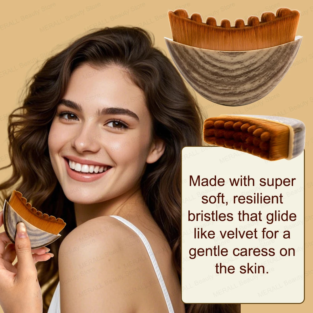 A woman holds a crescent-shaped face brush with a wood-grain handle and soft, brown, wavy-tipped bristles.