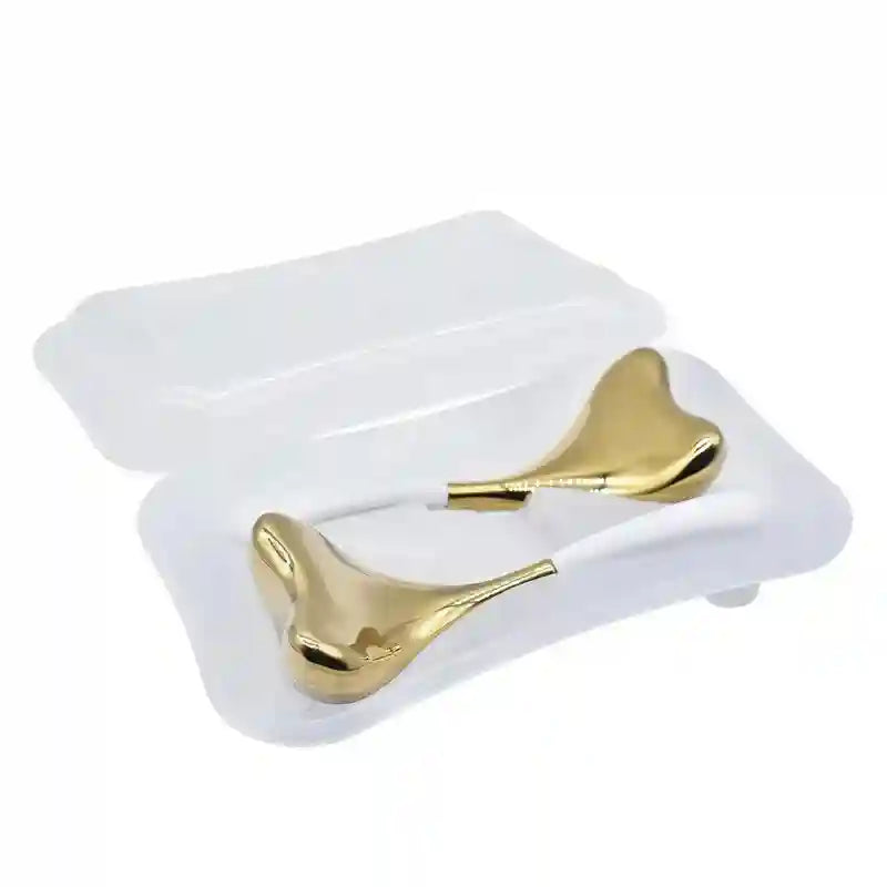 Two gold-toned, heart-shaped cryo sticks with white handles, resting in a clear plastic storage case.
