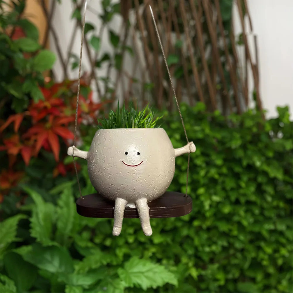Hanging swing succulent planter pot with smiling face and wooden round seat outdoors