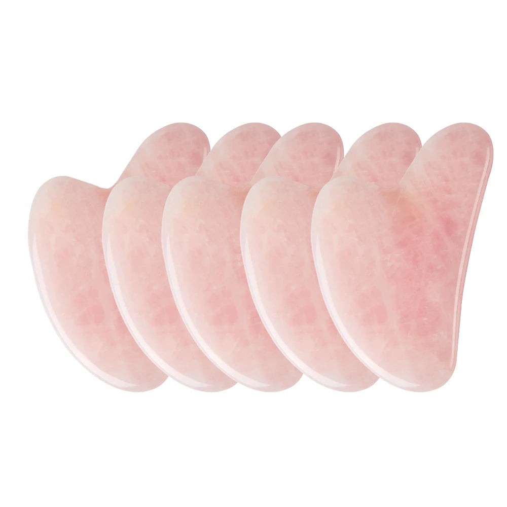 Five heart-shaped rose quartz gua sha facial massage tools with a smooth, polished pink stone texture.