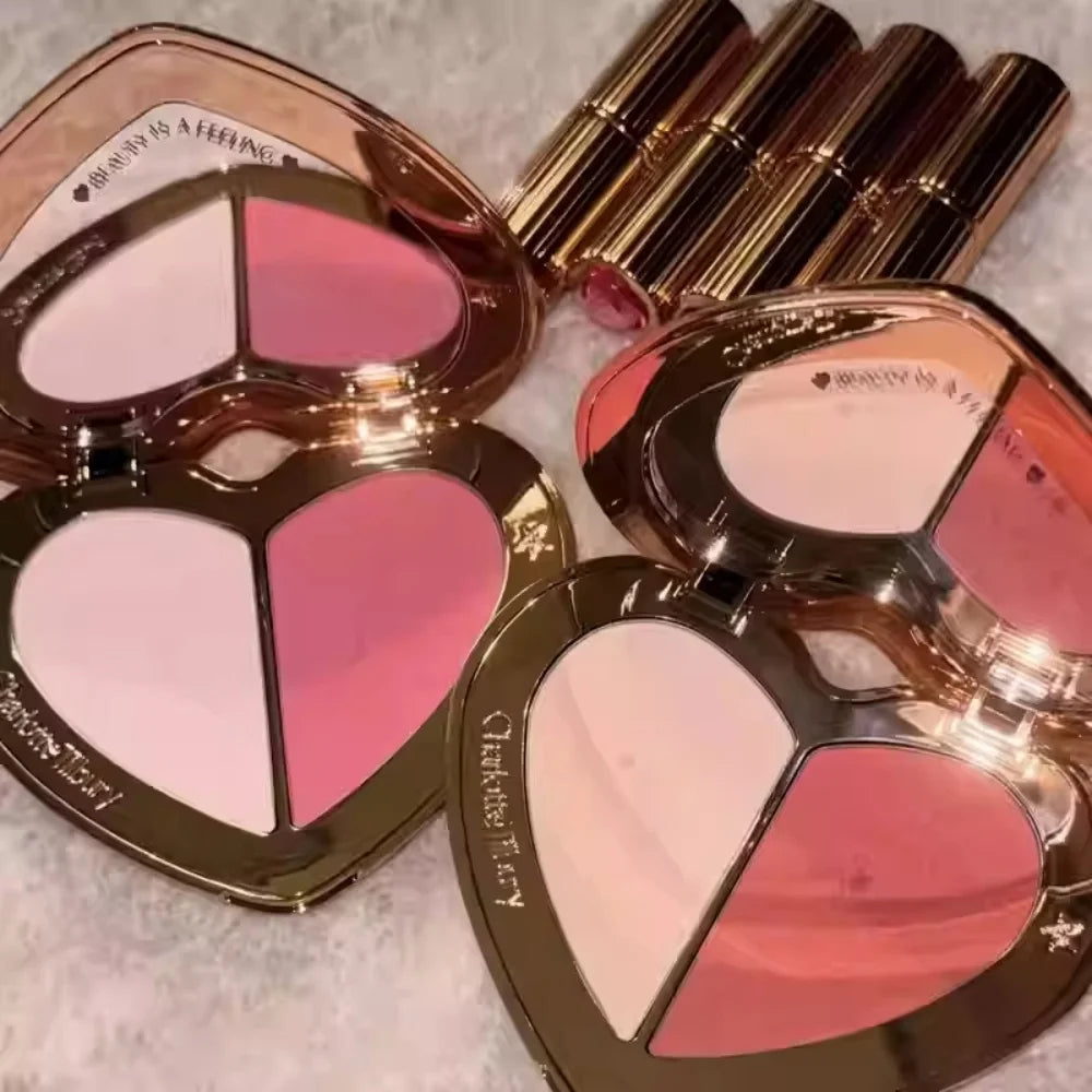 Charlotte Tilbury heart-shaped blush compacts with pink and coral powder shades and metallic gold lipstick tubes.