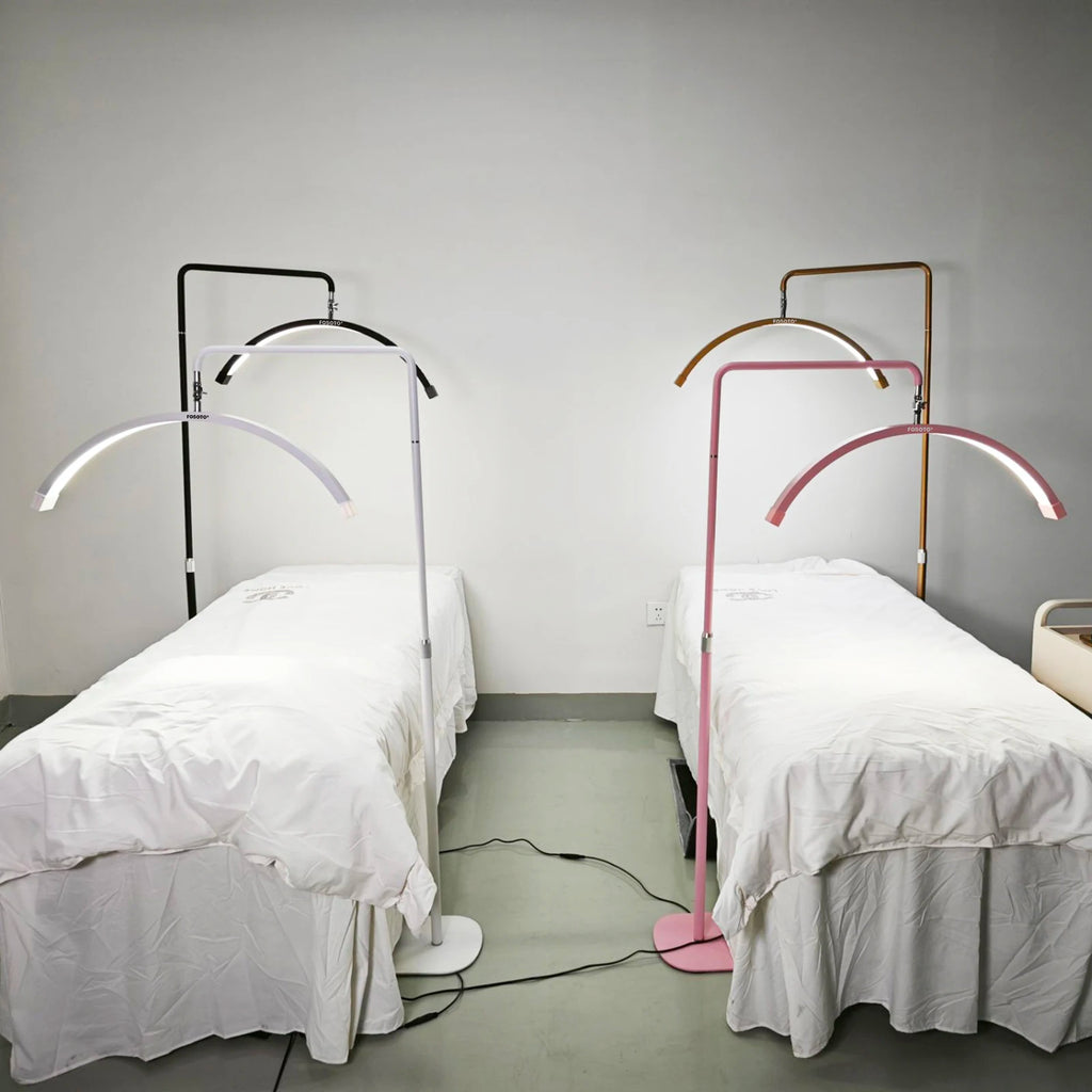 Crescent-shaped LED floor lamps with metal stands over spa beds, available in black, white, pink, and gold finishes.