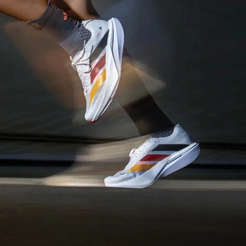 Adidas ZYRION PRO unisex running sneakers in white with red, yellow, and black stripes and thick carbon plate soles.