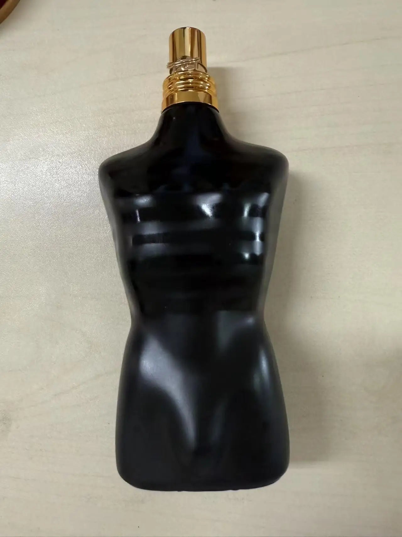 Jean Paul Gaultier Le Male Elixir men's parfum in iconic black torso bottle with gold cap. Luxury woody amber fragrance.