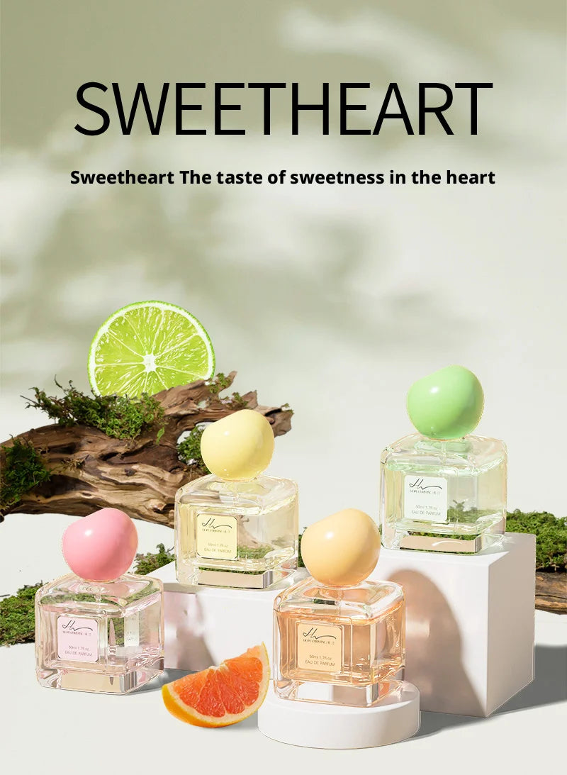 Four square glass perfume bottles with rounded pastel caps in pink, yellow, orange, and green on white display blocks.