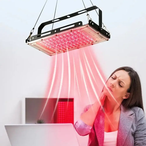 Rectangular red light therapy LED panel hanging above a woman to provide wellness pain relief therapy.