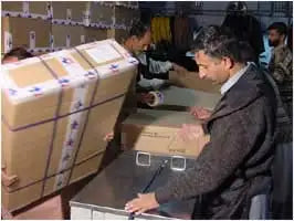 Men packing luxury leather business briefcase trunks in cardboard boxes for shipping. Professional storage facility.
