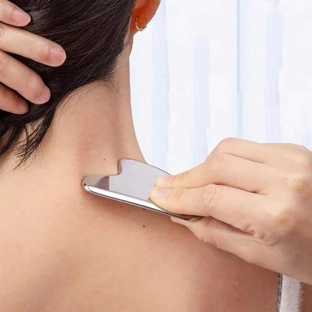 A hand uses a smooth, heart-shaped stainless steel gua sha tool to massage the side of a person's neck.