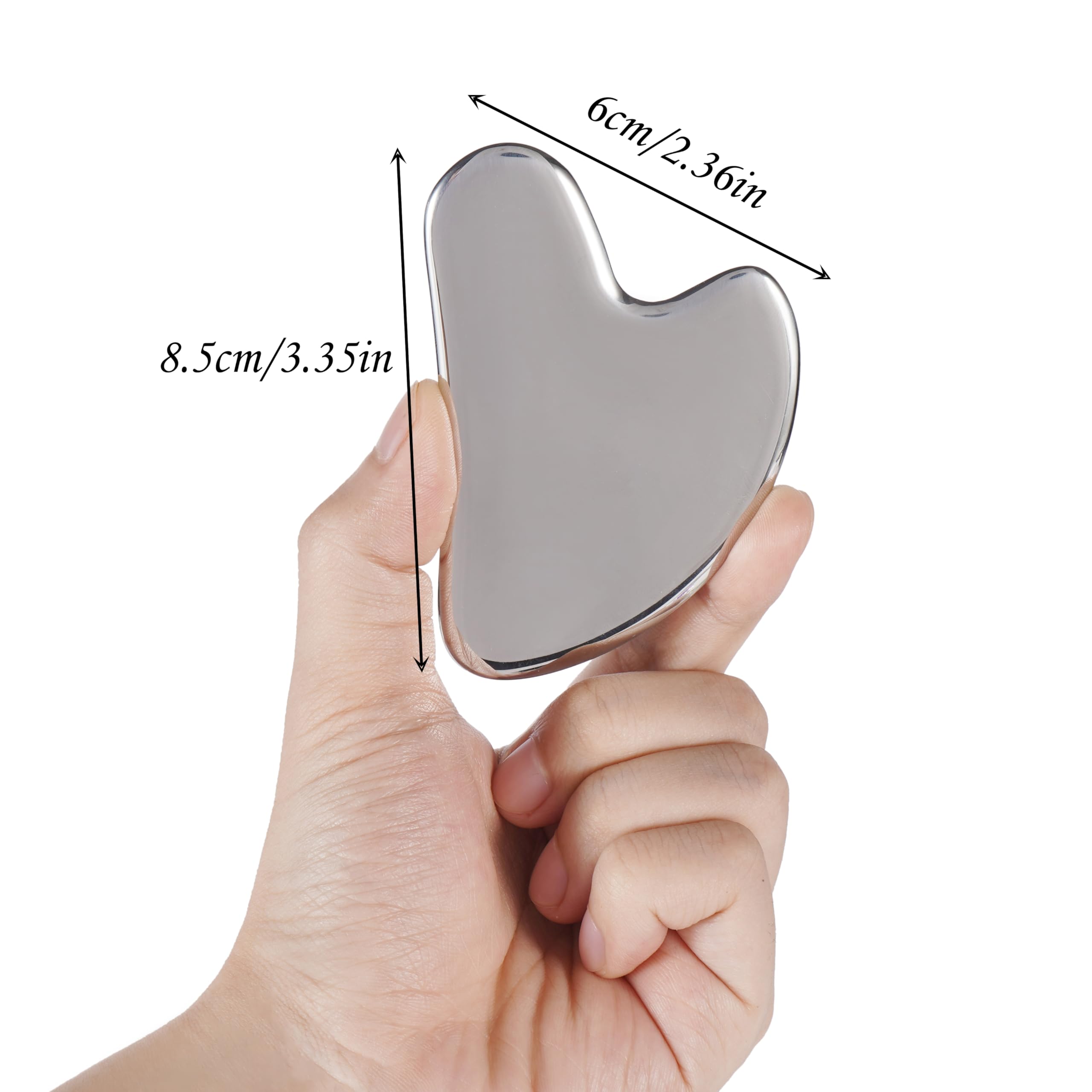 A hand holds a heart-shaped, polished silver stainless steel gua sha facial massage tool with measurement labels.